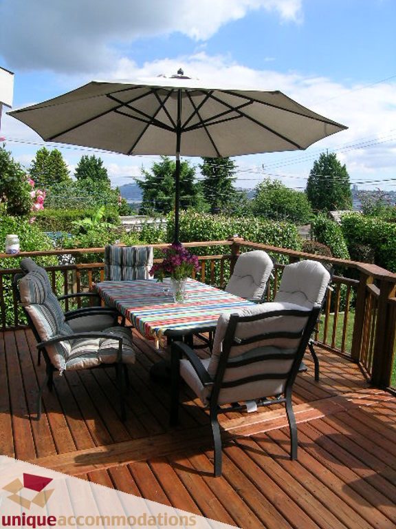Furnished patio with wooden deck, outdoor table, umbrella, and city view. - 813 - 5th Street East, North Vancouver