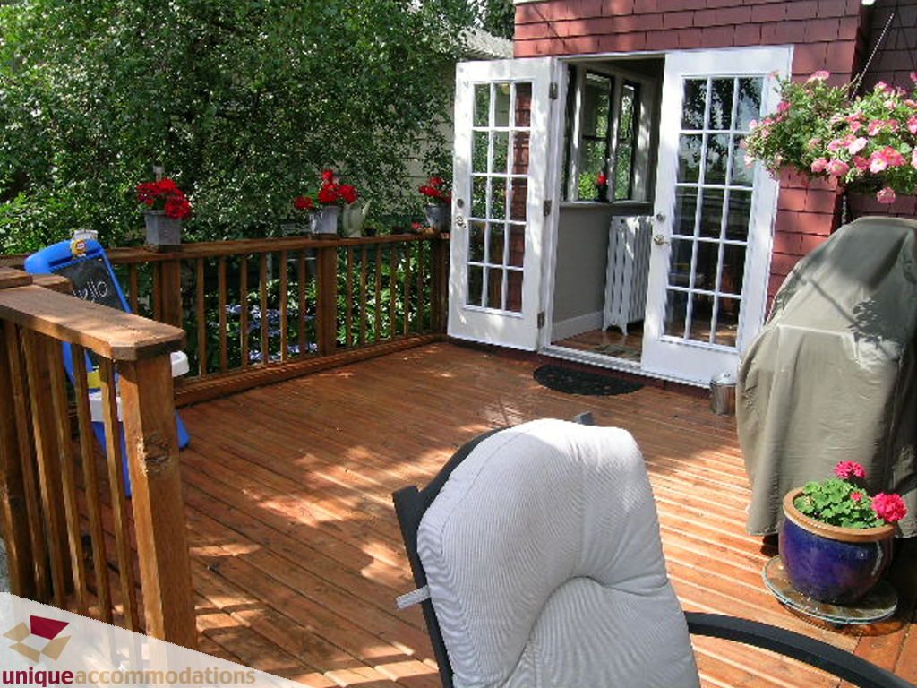 Furnished deck with wooden flooring, outdoor furniture, and potted flowers. - 813 - 5th Street East, North Vancouver
