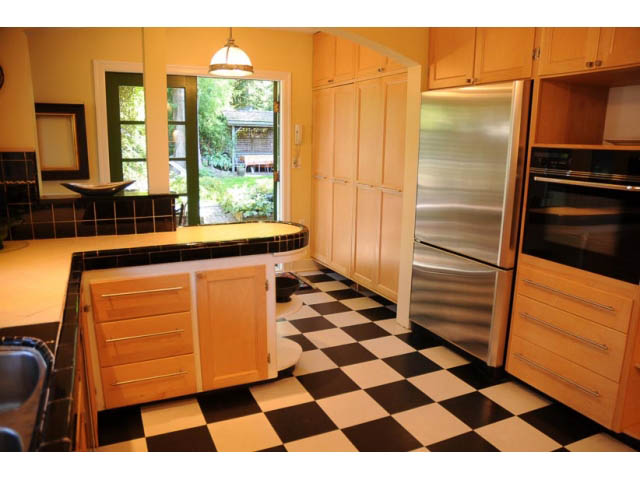Bright kitchen with black-and-white checkered floor, stainless steel appliances, and natural light from the back door.