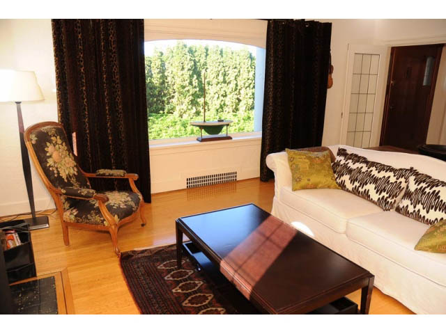 Furnished living room with hardwood floors, large window view, and patterned armchair. - 3998 West 10th Avenue, Vancouver West Side