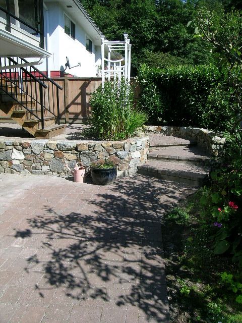 Furnished patio with stone wall, brick steps, and garden plants. - #2 (Upper) - 350 23rd St E, North Vancouver