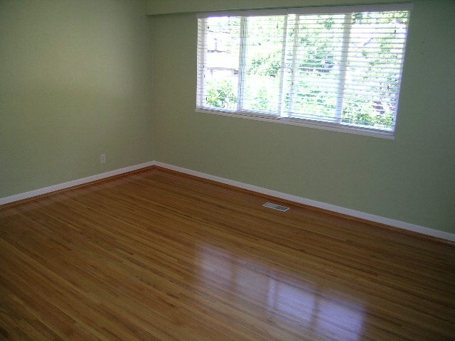 Bright living room with hardwood floors and large window view. - #2 (Upper) - 350 23rd St E, North Vancouver