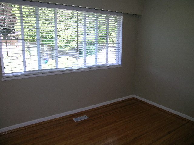 Bright living room with hardwood floors and blinds covering a large window. - #2 (Upper) - 350 23rd St E, North Vancouver
