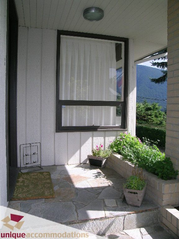 Bright sunroom with stone flooring, potted plants, and a view of the mountains. - 68 Bonnymuir Drive, West Vancouver