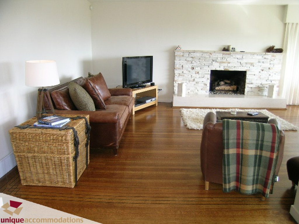Living room with hardwood floors, brick fireplace, and leather couches. - 68 Bonnymuir Drive, West Vancouver