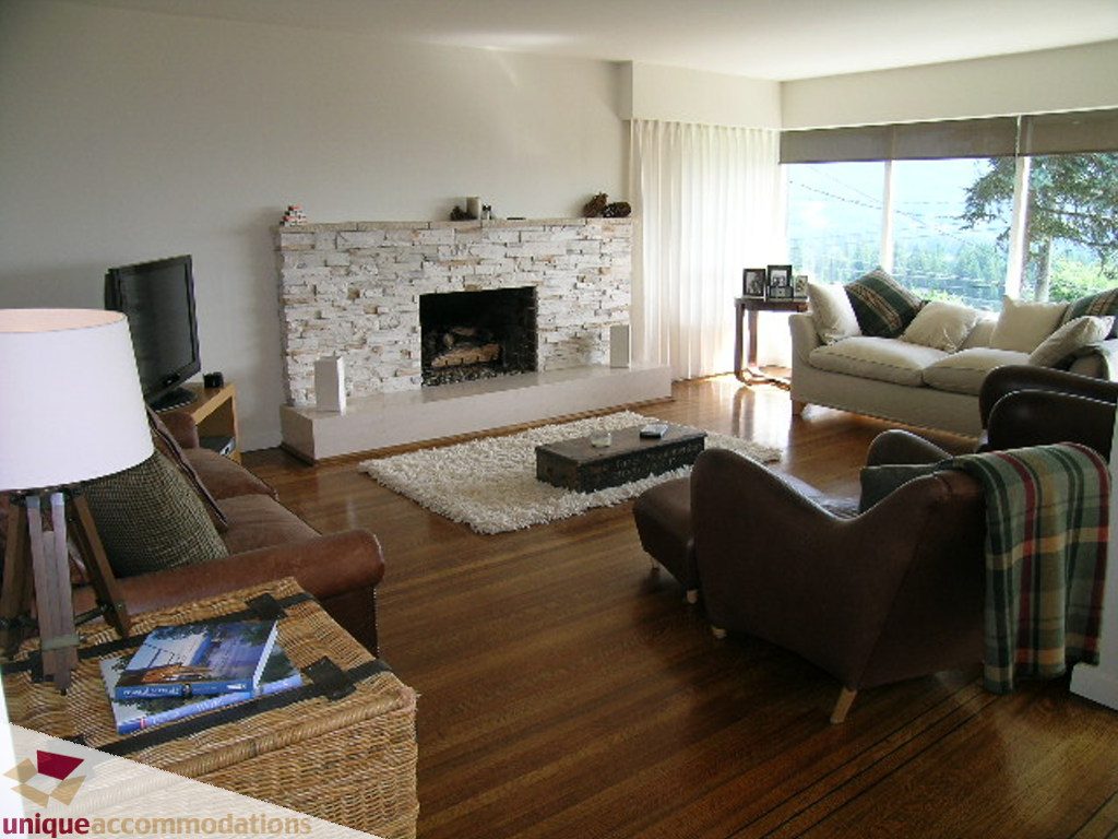 Spacious living room with hardwood floors, large windows, and a cozy fireplace. - 68 Bonnymuir Drive, West Vancouver