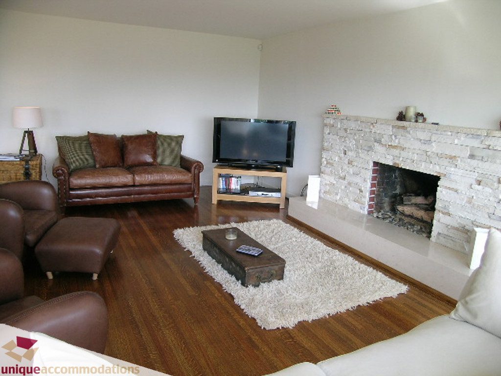 Living room with hardwood floors, brick fireplace, and leather furniture. - 68 Bonnymuir Drive, West Vancouver