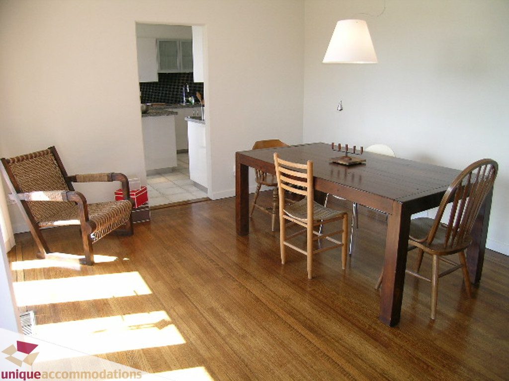 Bright dining area with hardwood floors and a kitchen in the background. - 68 Bonnymuir Drive, West Vancouver