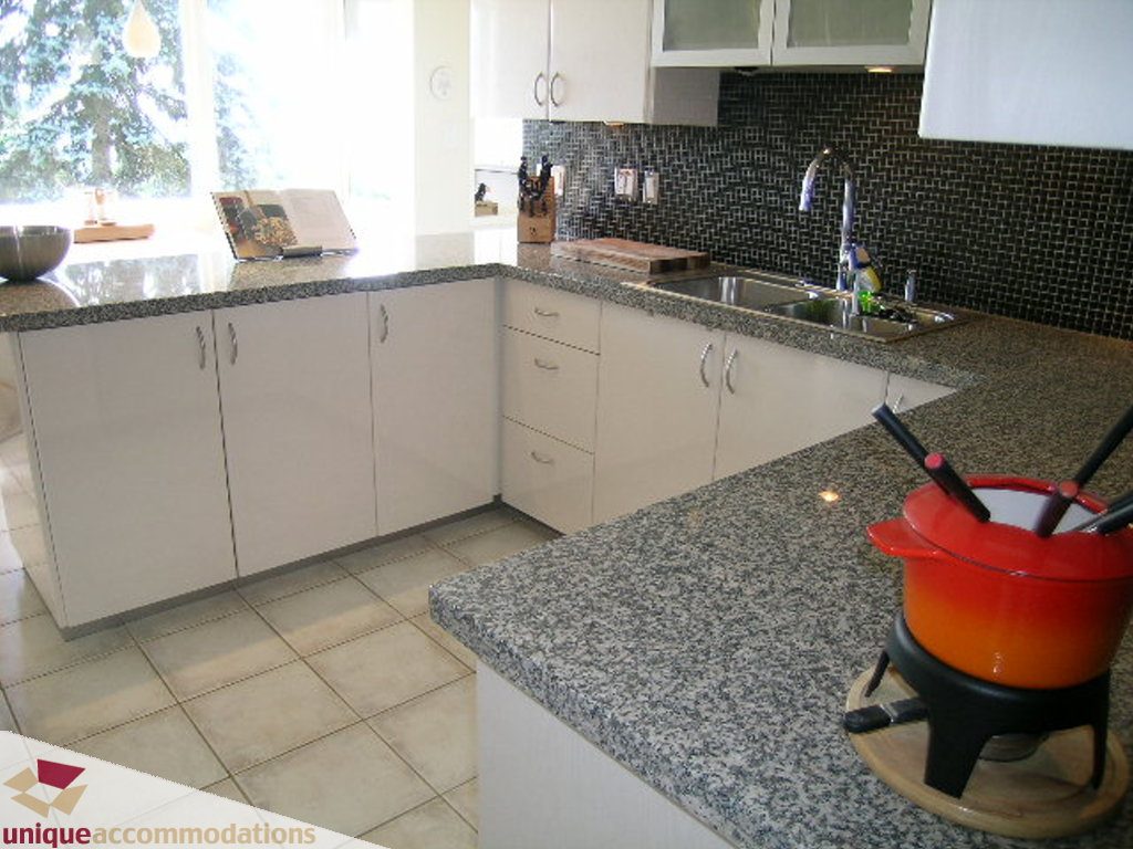 Bright kitchen with granite countertops and white cabinetry, featuring a red pot on the island. - 68 Bonnymuir Drive, West Vancouver