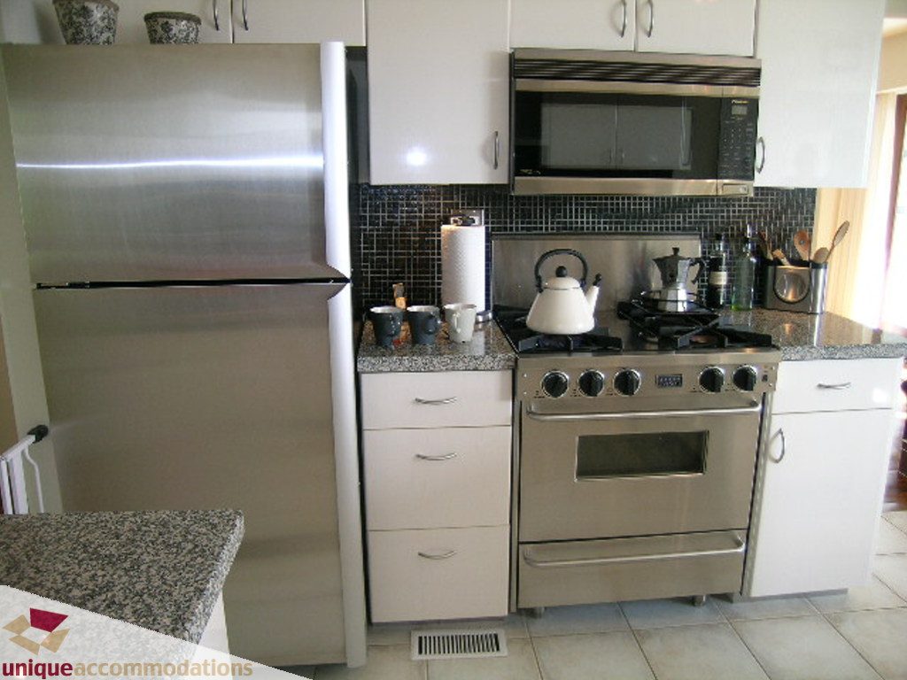 Bright kitchen with stainless steel appliances, granite countertops, and white cabinets. - 68 Bonnymuir Drive, West Vancouver
