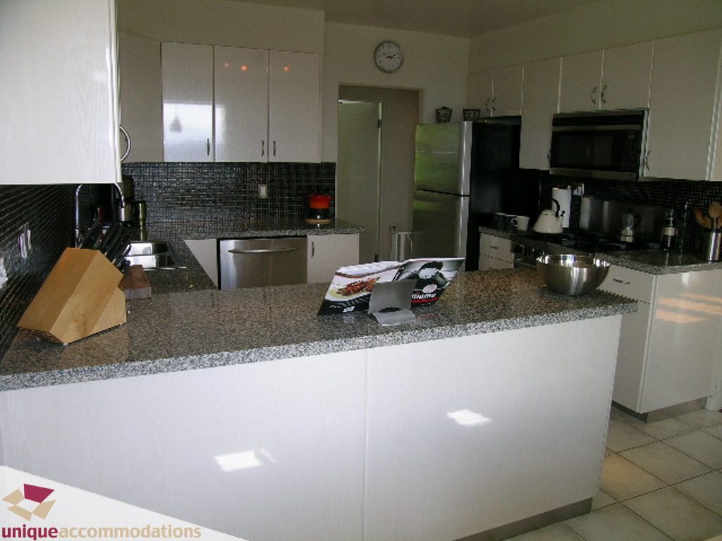 Bright kitchen with granite countertops and white cabinetry, modern appliances, and a central island. - 68 Bonnymuir Drive, West Vancouver