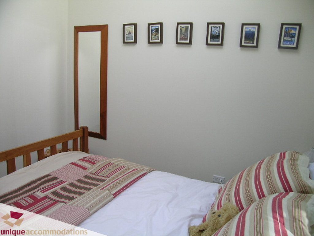 Cozy bedroom with twin beds, wooden headboards, and framed artwork on the wall. - 68 Bonnymuir Drive, West Vancouver