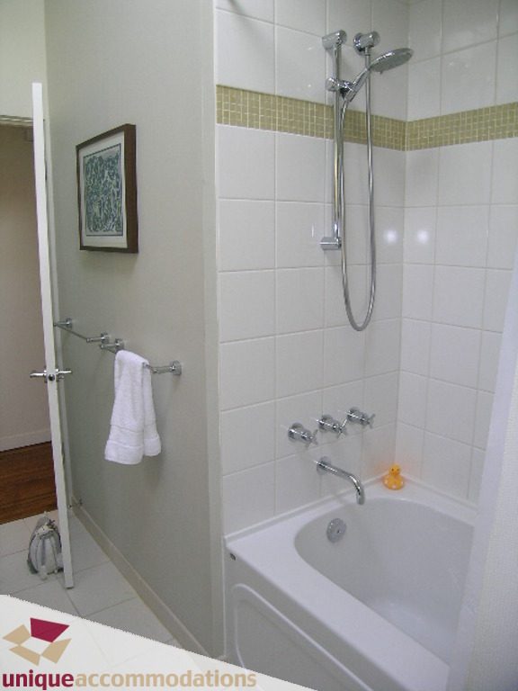 Bathroom with white tiles, shower, and towel rack. - 68 Bonnymuir Drive, West Vancouver