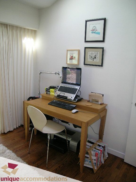 Bright home office with wooden desk, laptop, and framed art on the wall. - 68 Bonnymuir Drive, West Vancouver
