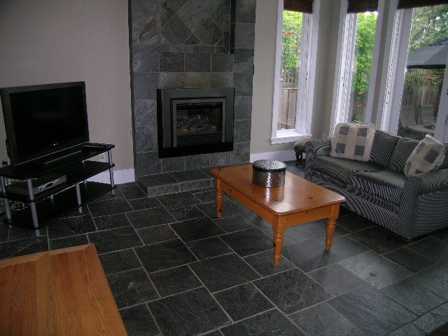 Living room with dark stone fireplace, hardwood flooring, and large windows. - 3670 Point Grey Road, Vancouver West Side
