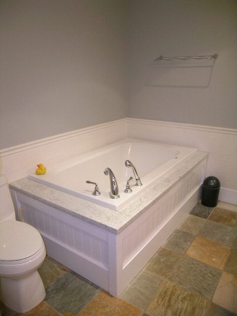 Bathroom with white tub, marble countertop, and tiled floor. - 3670 Point Grey Road, Vancouver West Side