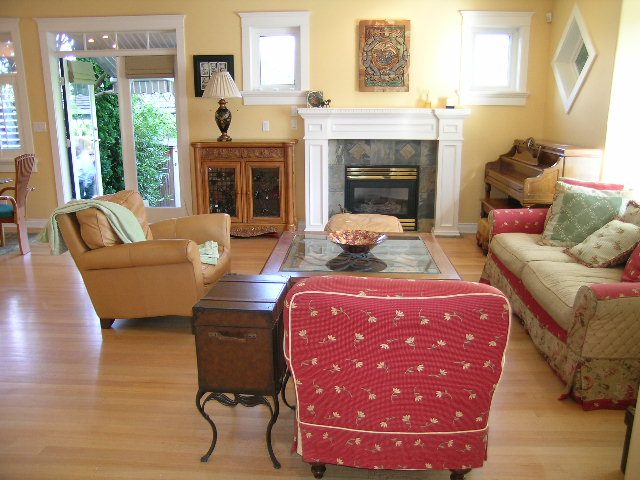 Living room with hardwood floors, fireplace, and red patterned furniture. - 3077 West 2nd Avenue, Vancouver West Side