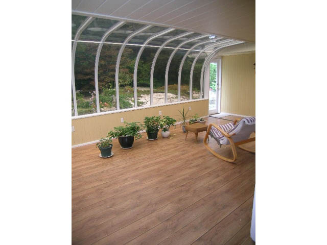 Bright sunroom with curved glass walls, hardwood floors, and potted plants. - 5725 Cranley Drive, West Vancouver