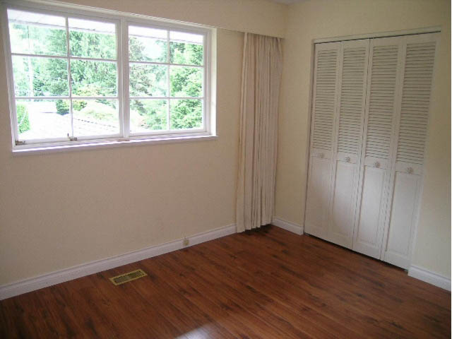 Bright bedroom with hardwood floors and large window, white closet doors. - 5725 Cranley Drive, West Vancouver