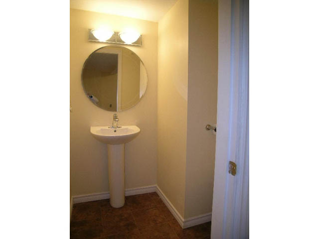 Bathroom with pedestal sink, round mirror, and wall-mounted lights. - 5725 Cranley Drive, West Vancouver