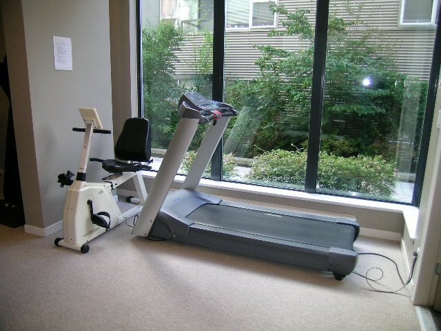 Bright living room with large windows, exercise equipment, and city view. - 305 - 2228 Marstrand Avenue, Vancouver West Side