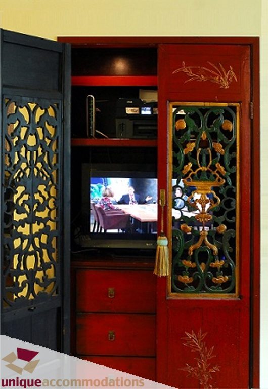 Bright living room with ornate red cabinet and TV, decorative doors. - T15 - 1501 Howe Street, Vancouver Downtown