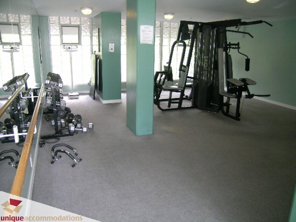 Bright gym with cardio machines and weight racks, carpeted floor. - T15 - 1501 Howe Street, Vancouver Downtown