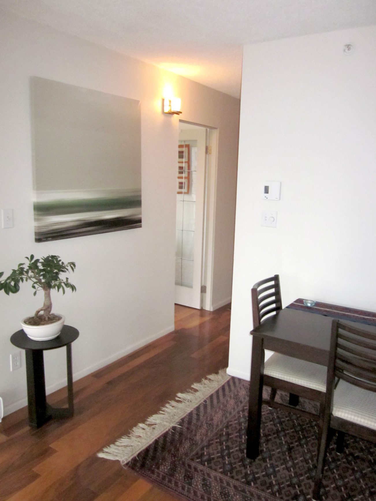 Furnished dining area with hardwood floors, small table, and wall art. - 1403 - 907 Beach Avenue, Vancouver Downtown