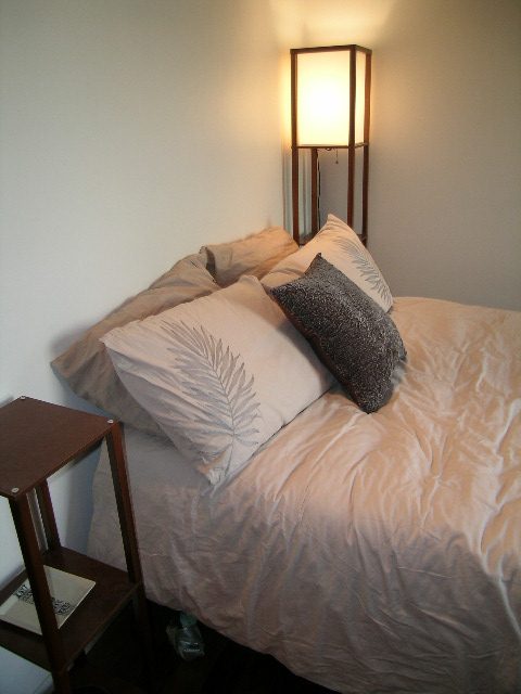 Furnished bedroom with cozy bedding and a floor lamp, featuring a nightstand. - 1403 - 907 Beach Avenue, Vancouver Downtown