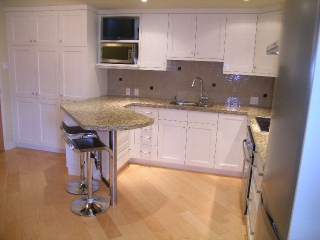 Bright kitchen with granite countertops, hardwood floors, and a small island, perfect for a cozy downtown condo.