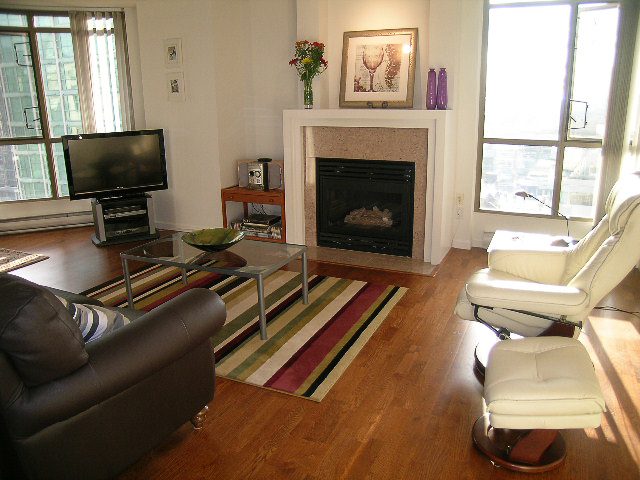 Bright living room with hardwood floors, city view, and a cozy fireplace. - 1701 - 867 Hamilton Street, Vancouver Downtown