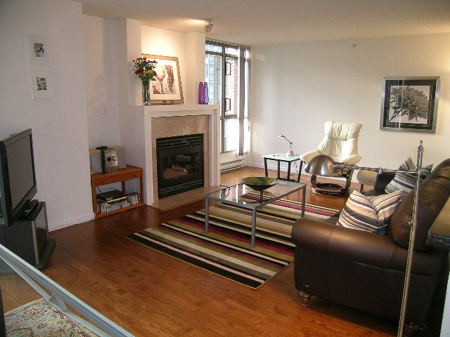 Bright living room with hardwood floors, striped rug, and city view through large windows. - 1701 - 867 Hamilton Street, Vancouver Downtown