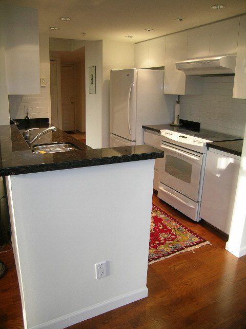Bright kitchen with black countertops, white cabinets, and hardwood floors. - 1701 - 867 Hamilton Street, Vancouver Downtown