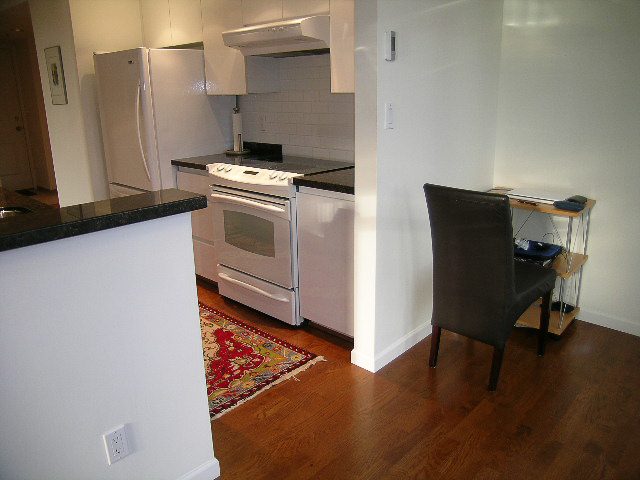 Bright kitchen with black countertops, hardwood floors, and a cozy corner desk. - 1701 - 867 Hamilton Street, Vancouver Downtown