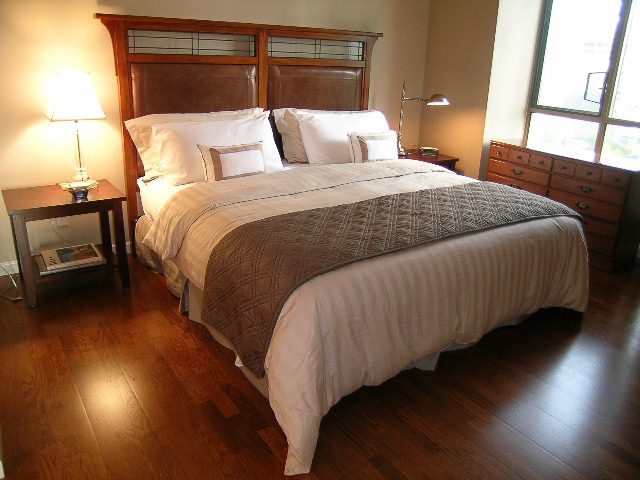 Furnished 2-bedroom condo with hardwood floors and a cozy bed setup. - 1701 - 867 Hamilton Street, Vancouver Downtown
