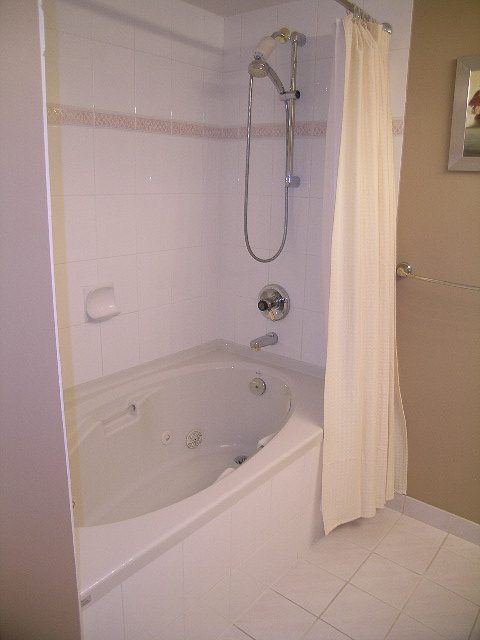 Bright bathroom with white tiles and a corner shower. - 1701 - 867 Hamilton Street, Vancouver Downtown