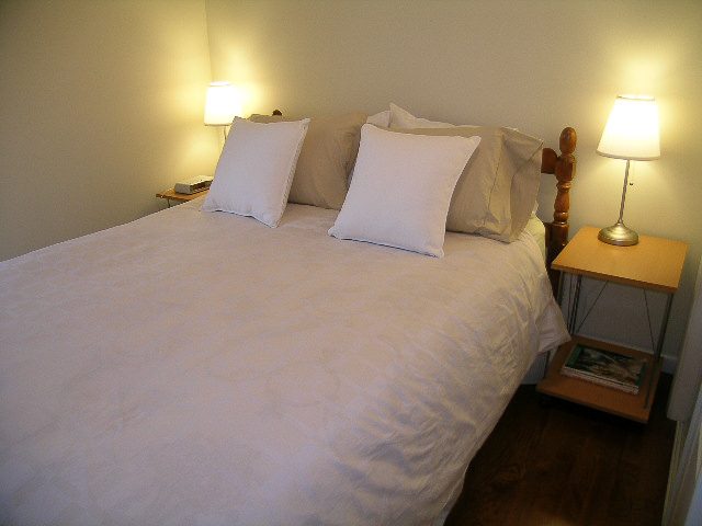 Furnished 2-bedroom condo with cozy bed setup, hardwood floors, and bedside lamps. - 1701 - 867 Hamilton Street, Vancouver Downtown