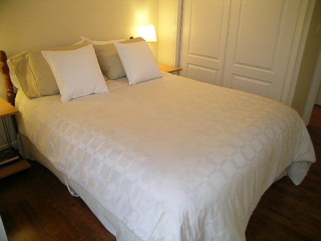 Furnished 2-bedroom bedroom with white bedding and wooden floors. - 1701 - 867 Hamilton Street, Vancouver Downtown