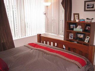 Bright bedroom with wooden furniture, red bedding, and a large window with blinds. - 2901-1438 Richards Street, Vancouver Downtown