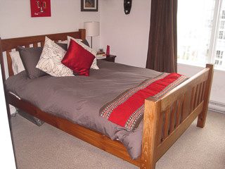 Furnished 1-bedroom + den with twin beds, red and gray bedding, and natural light from large windows. - 2901-1438 Richards Street, Vancouver Downtown