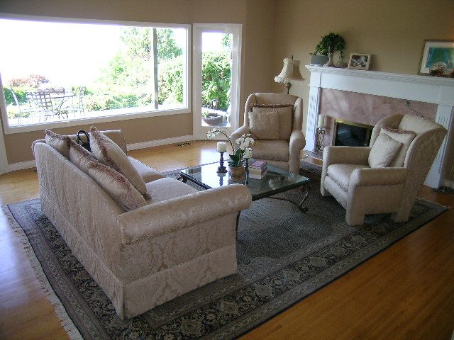 Bright living room with hardwood floors, large windows, and a cozy fireplace. - 1332 Camridge Place, West Vancouver