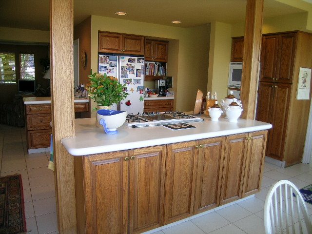 Bright kitchen with wooden cabinets, white countertops, and a cozy corner nook. - 1332 Camridge Place, West Vancouver