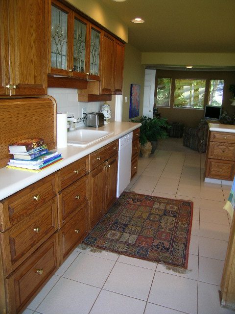 Bright kitchen with wooden cabinets, white countertops, and a patterned rug. - 1332 Camridge Place, West Vancouver