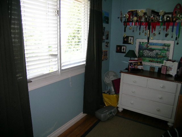 Bright bedroom with light blue walls, white dresser, and window with blinds. - 1332 Camridge Place, West Vancouver
