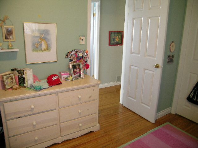 Bright bedroom with hardwood floors and a white dresser, featuring a framed rabbit picture and a pink rug. - 1332 Camridge Place, West Vancouver