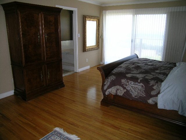 Furnished bedroom with hardwood floors and a large armoire. - 1332 Camridge Place, West Vancouver