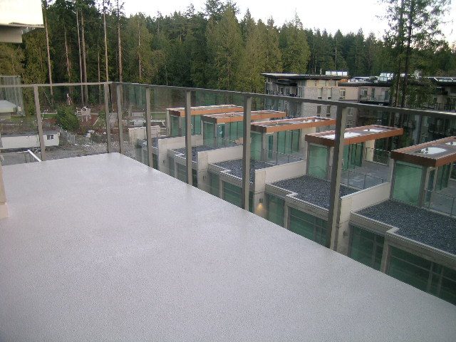 Spacious balcony with glass railings, surrounded by greenery. - 602 - 5782 Berton Avenue, Vancouver West Side