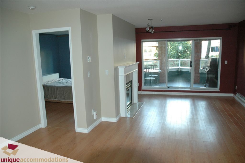 Spacious living room with hardwood floors and sliding glass door to balcony. - 208 - 128 West 8th Street, North Vancouver
