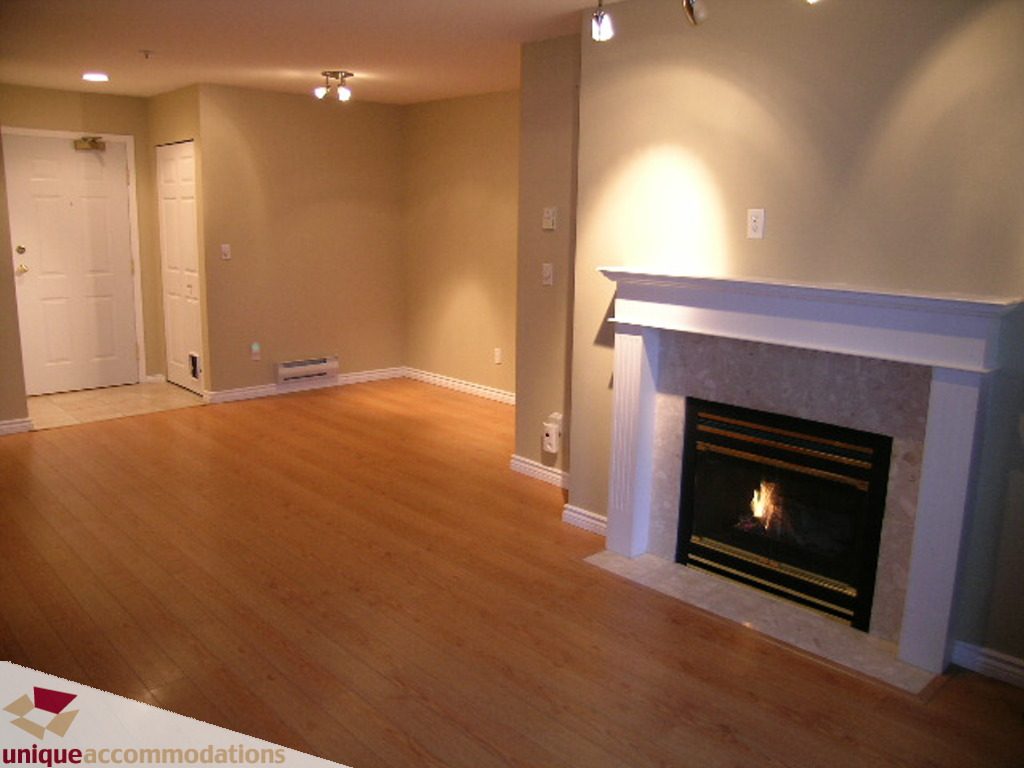 Furnished living room with hardwood floors and a fireplace, ready for move-in. - 208 - 128 West 8th Street, North Vancouver