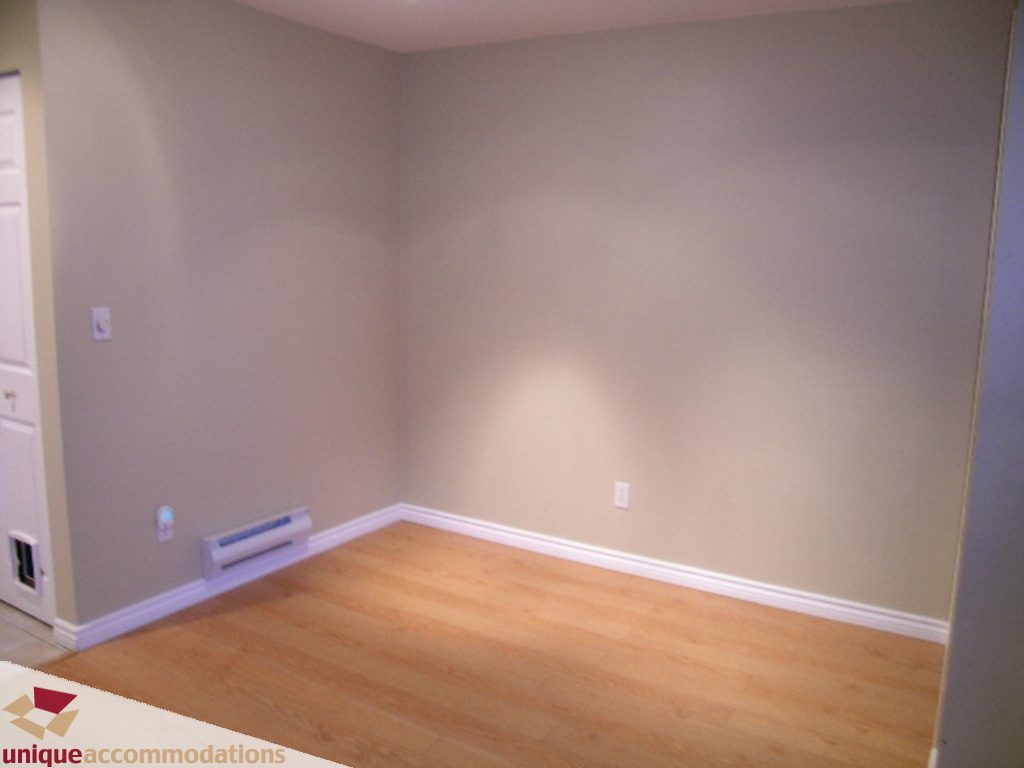 Empty living room with hardwood floors and neutral walls. - 208 - 128 West 8th Street, North Vancouver